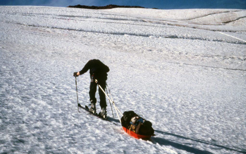 Person with skis pulling a sledge and equipment in the snow