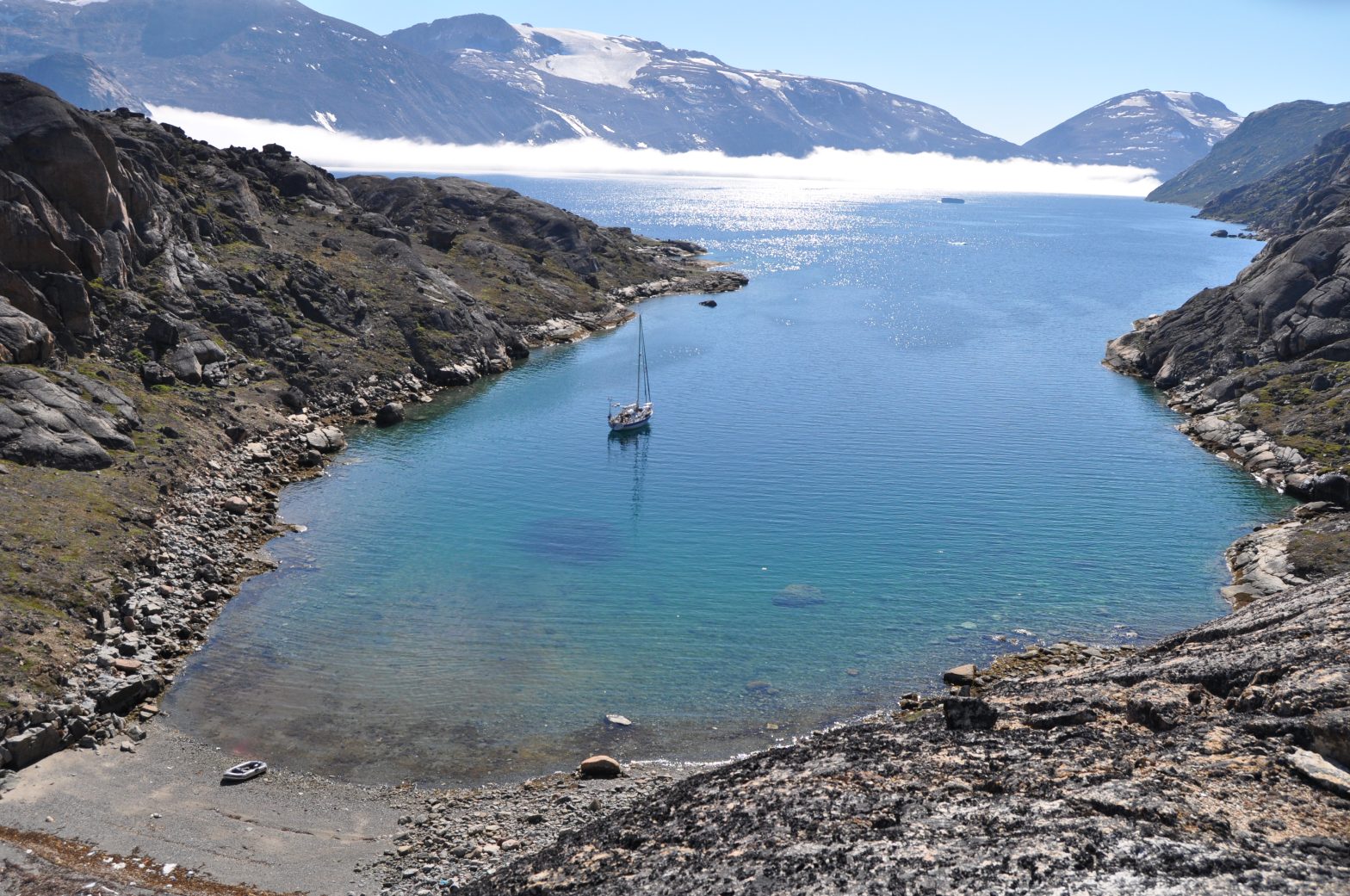 Boat anchored in a large fjord surrounded by mountains
